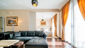 Ein modernes Wohnzimmer mit einer Eckcouch, einem kleinen Couchtisch und einem großen Fenster mit Vorhängen.