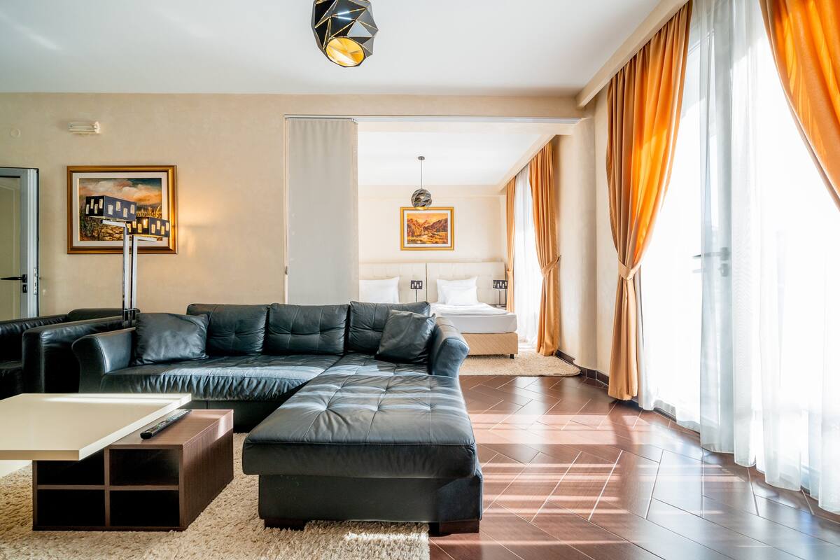 A modern living room with a sectional sofa, a small coffee table, and a large window with curtains.