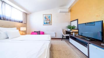 Habitació d'hotel amb un llit, una televisió, una taula i una planta.