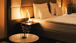 Ein Hotelzimmer mit einem großen Bett, einem Nachttisch mit Lampe, einem kleinen runden Tisch und einem Sessel.