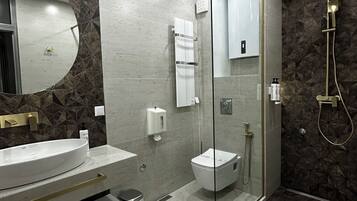 Une salle de bain moderne avec un grand miroir ovale, une douche à parois de verre et des toilettes.