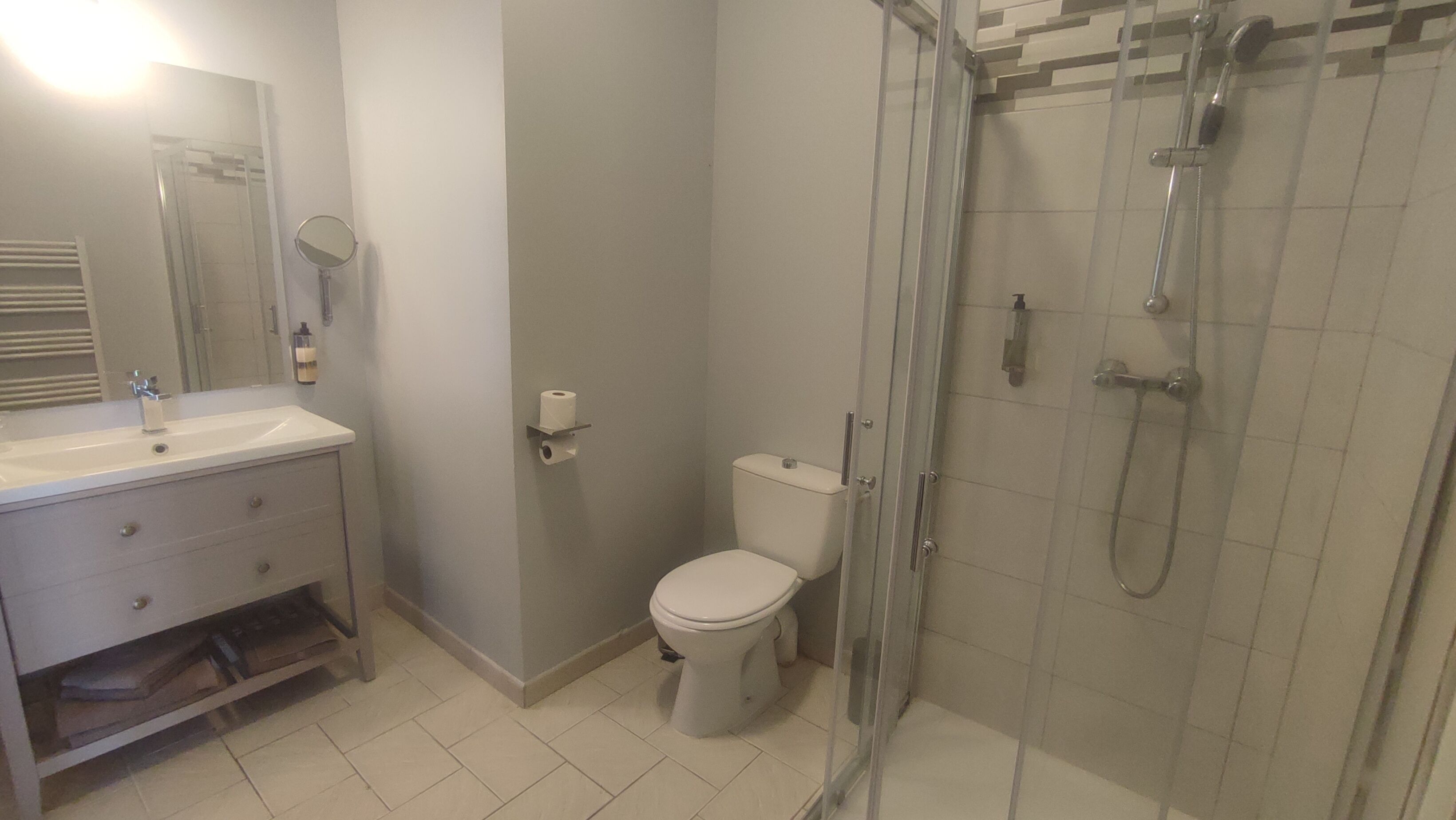 A bathroom with a sink, mirror, toilet, and glass-enclosed shower.