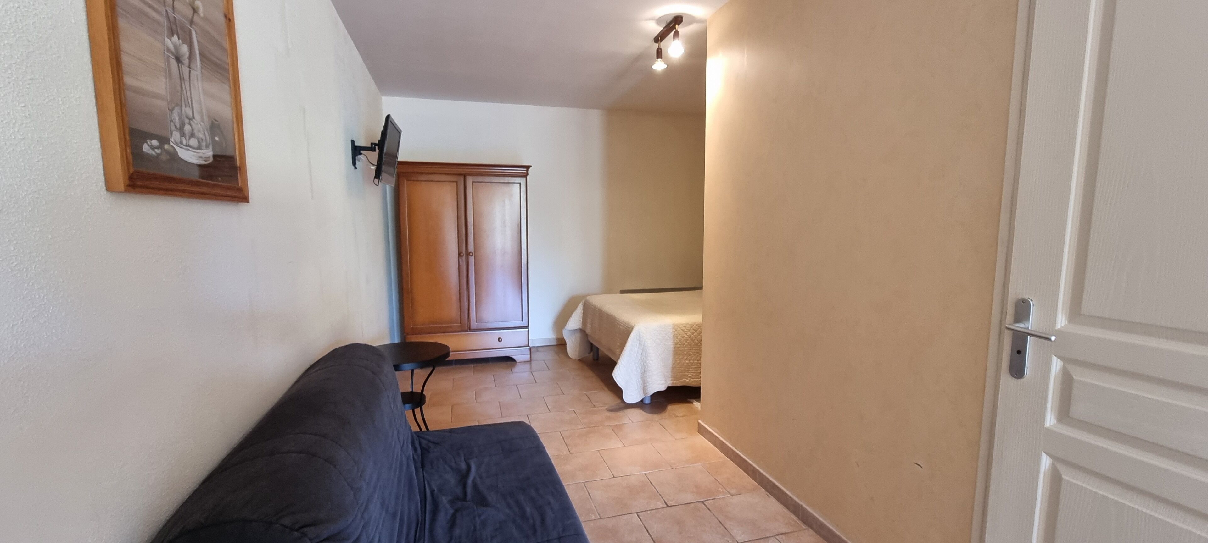 Un pasillo estrecho con un sofá, un armario y una cama.