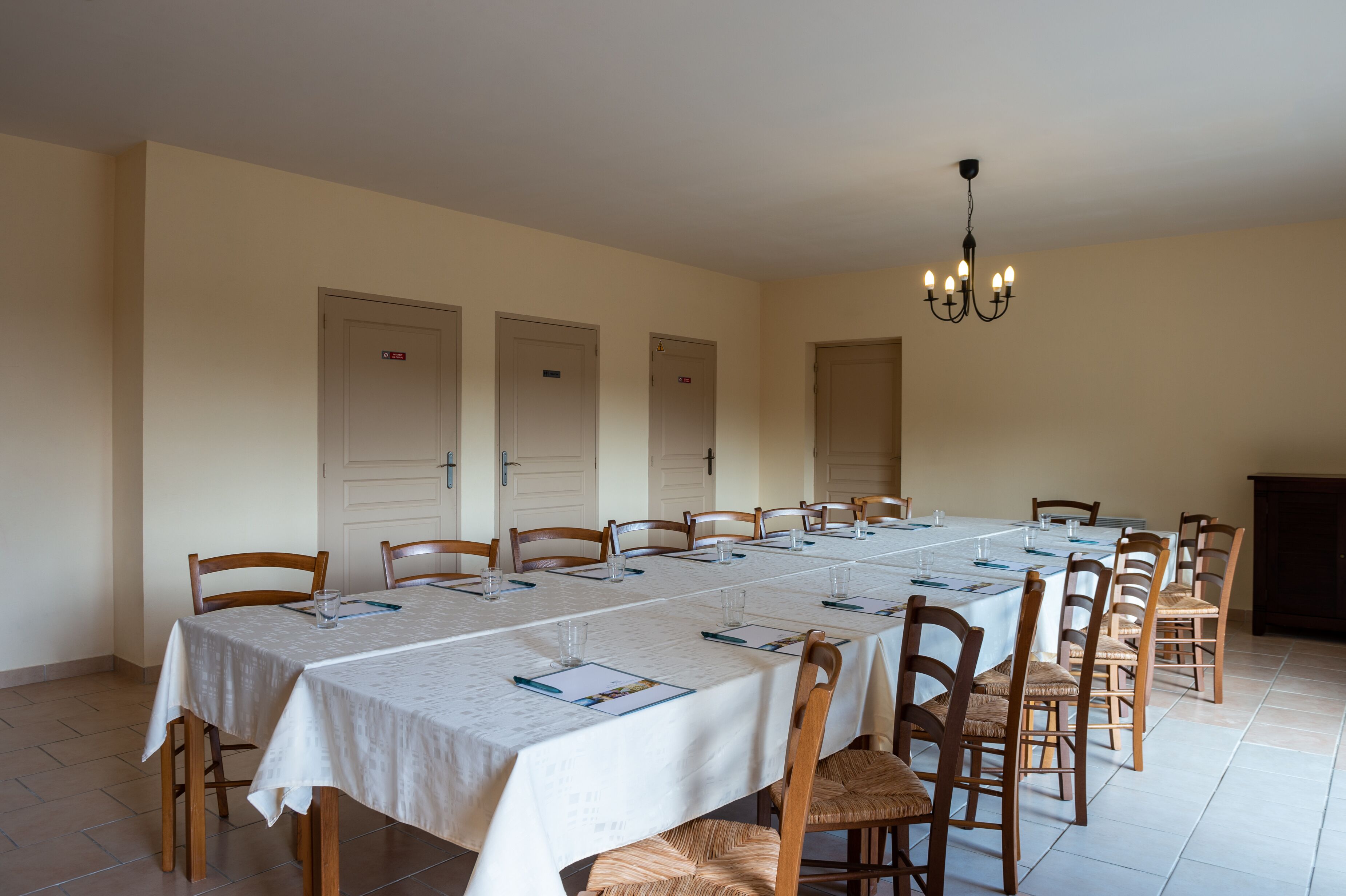 A dining room with a long table set for multiple people, wooden chairs, and a chandelier.