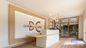 A reception desk with a modern design, a glass door entrance, and a visible interior space with seating.