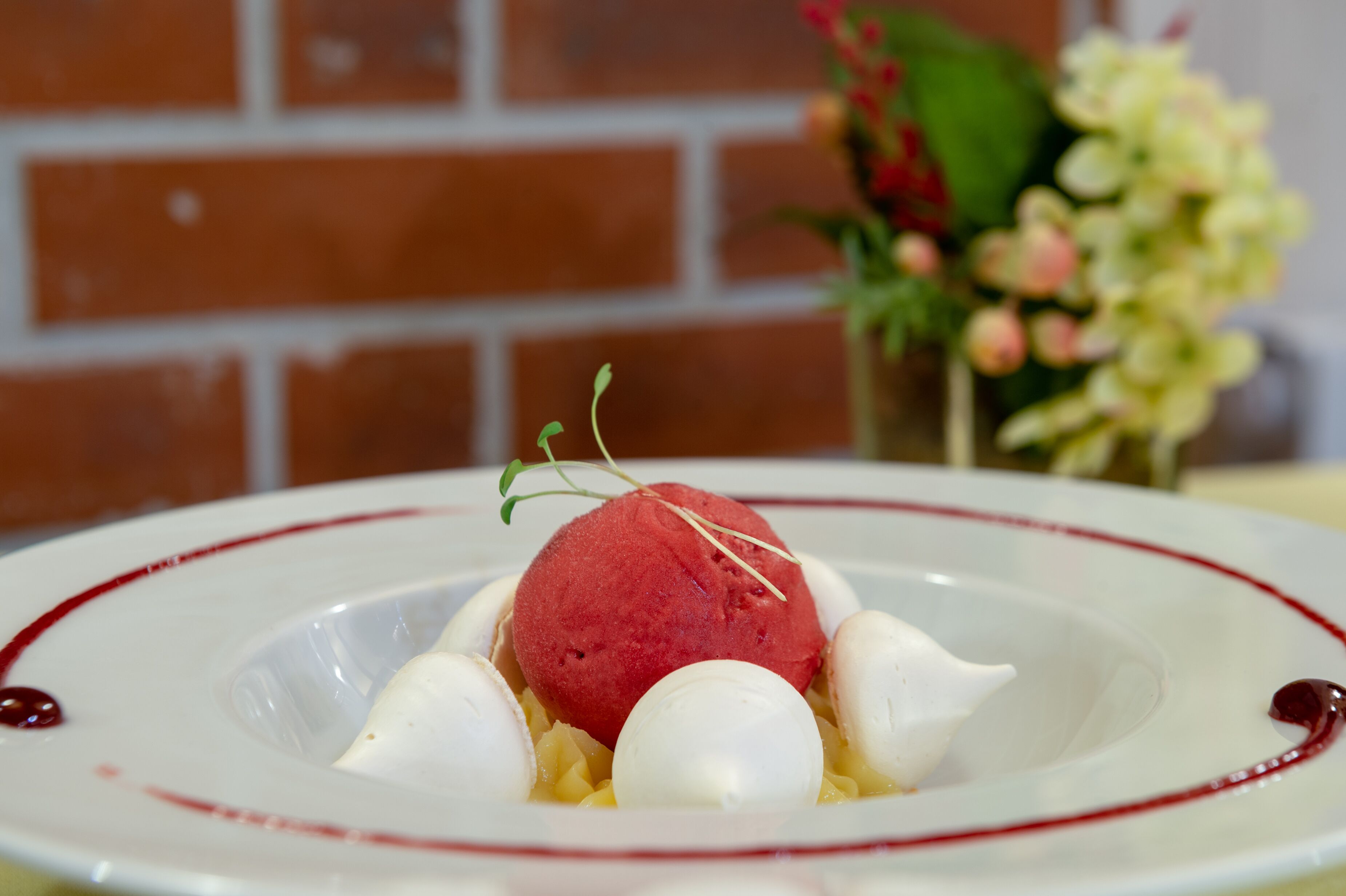 Ein Dessertteller mit einer roten Kugel, weißen Kugeln und einem roten Rand.