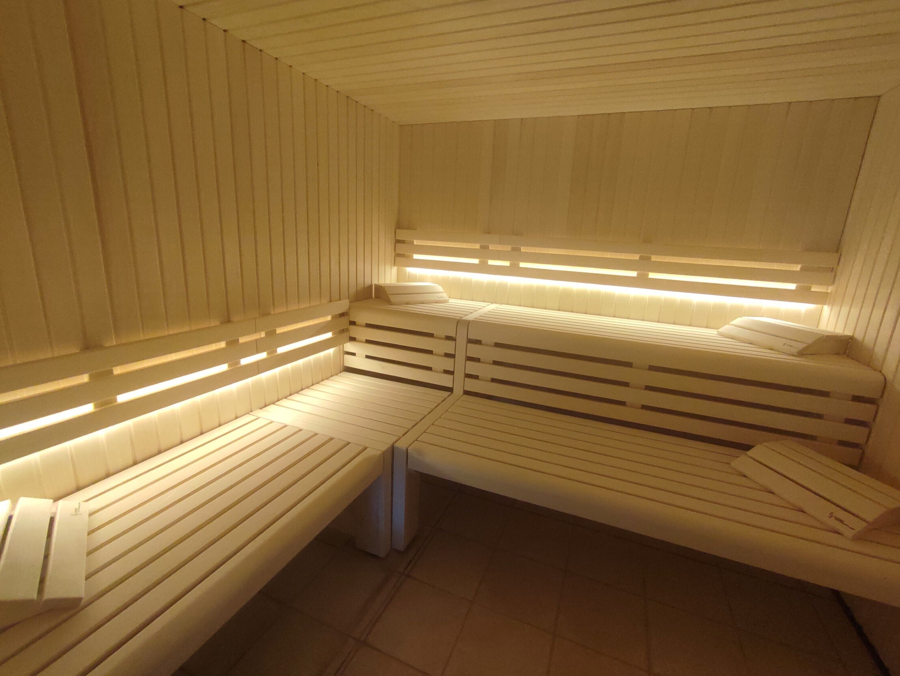 A modern spa room with a wooden bench and a massage table, both with built-in lighting.