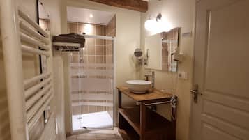 Un bany amb dutxa, un lavabo, un mirall i un suport per a tovalloles.