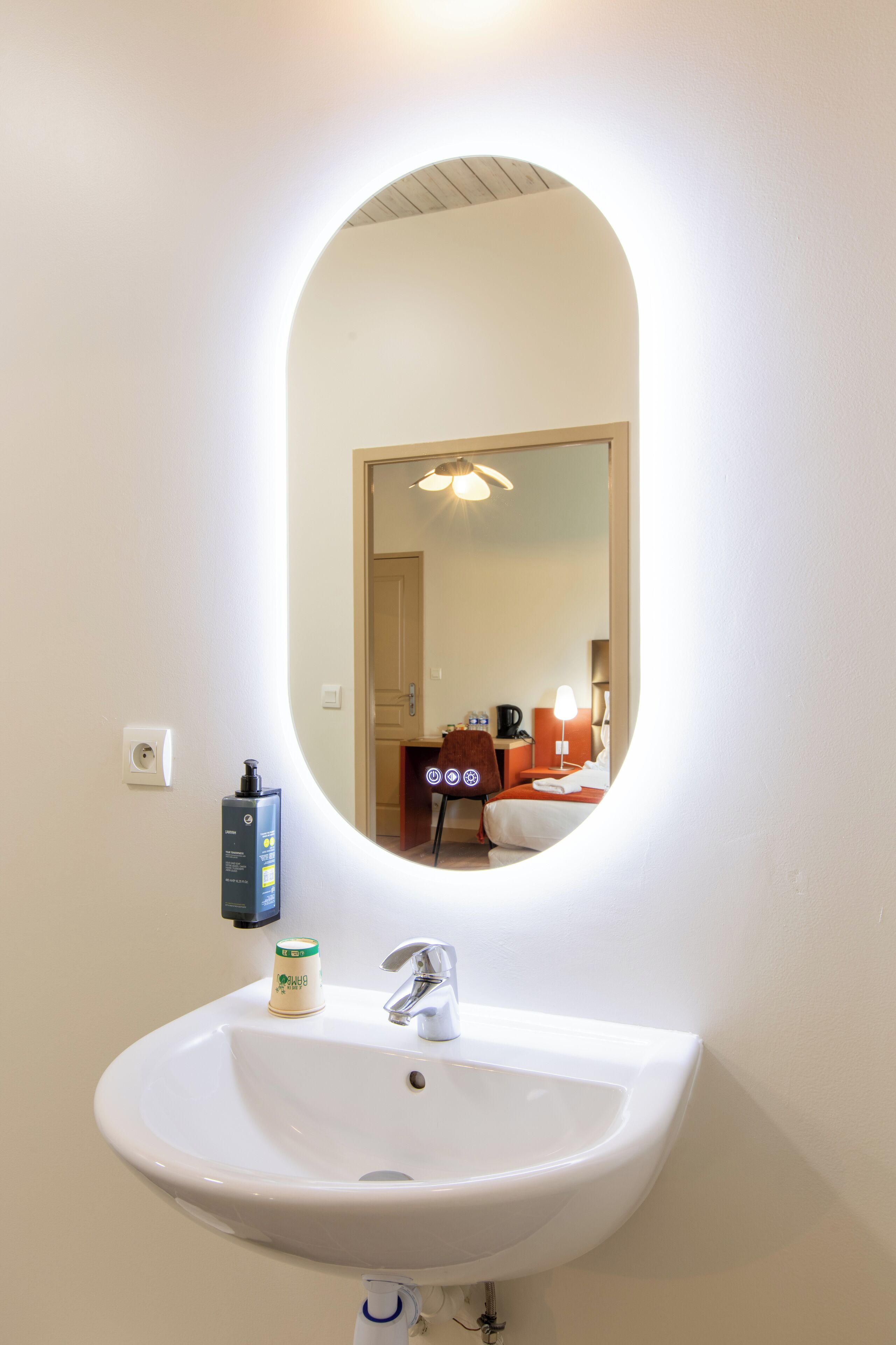 A bathroom with a white sink, a mirror, and a hand soap dispenser.