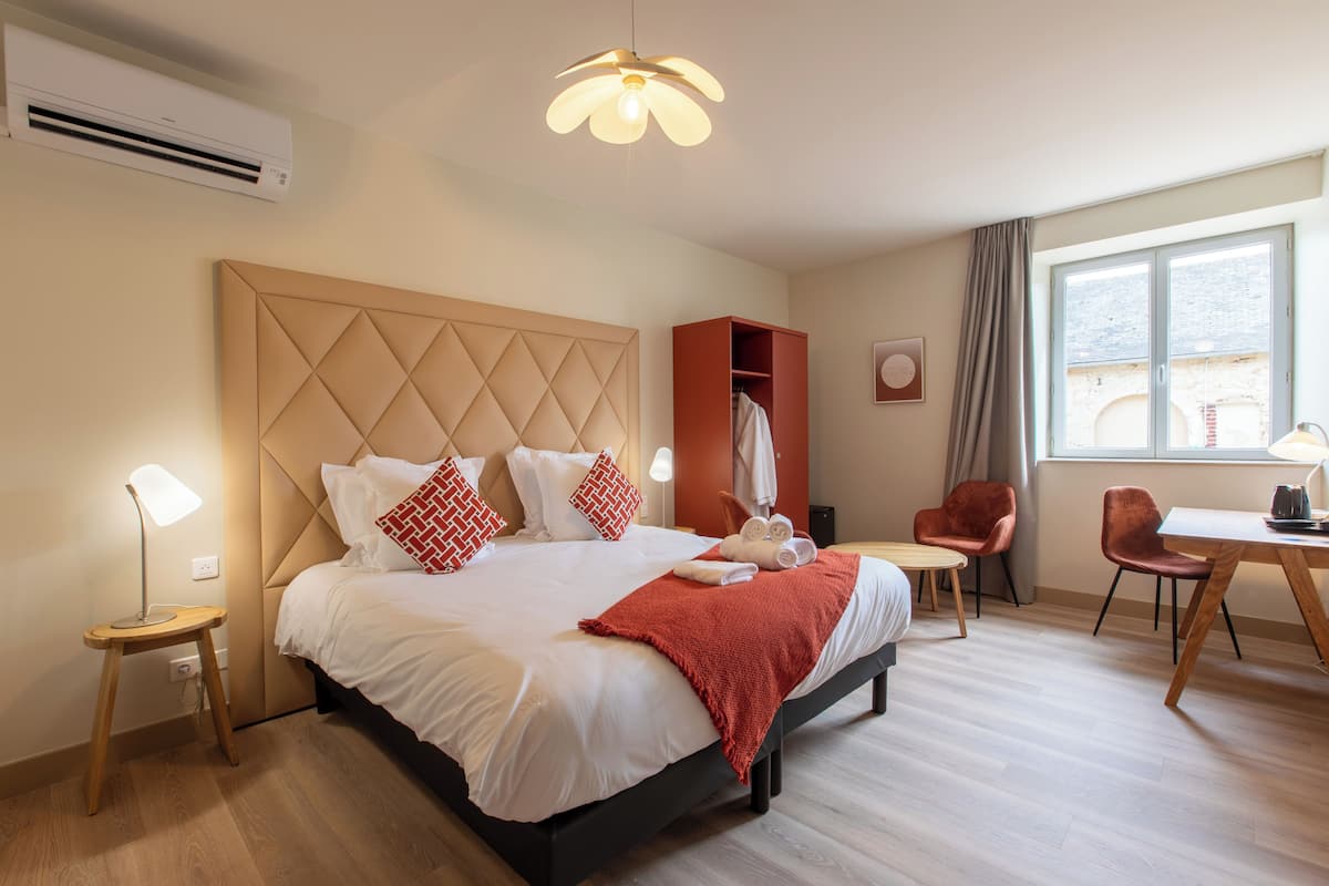 A modern hotel room with a large bed, a desk, and a chair.