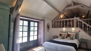 A bedroom with a large bed, a staircase, and a window with curtains.