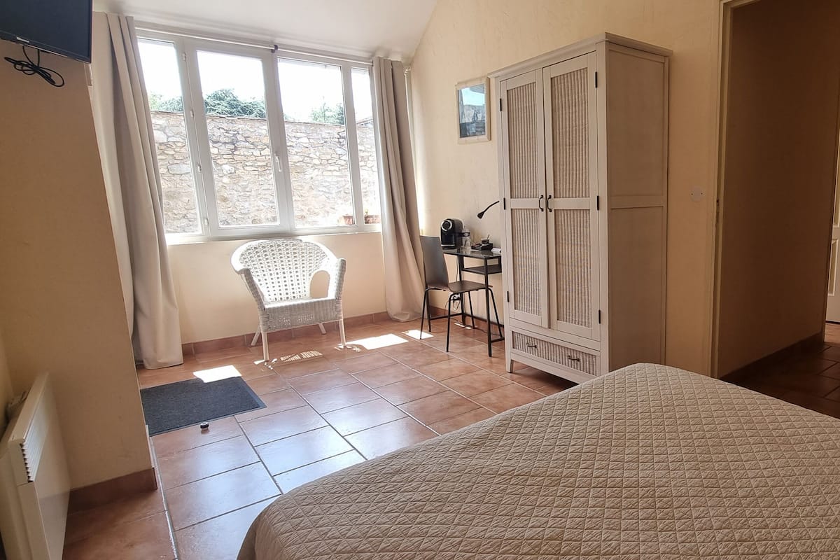 A bedroom with a bed, a chair, a desk, and a wardrobe.