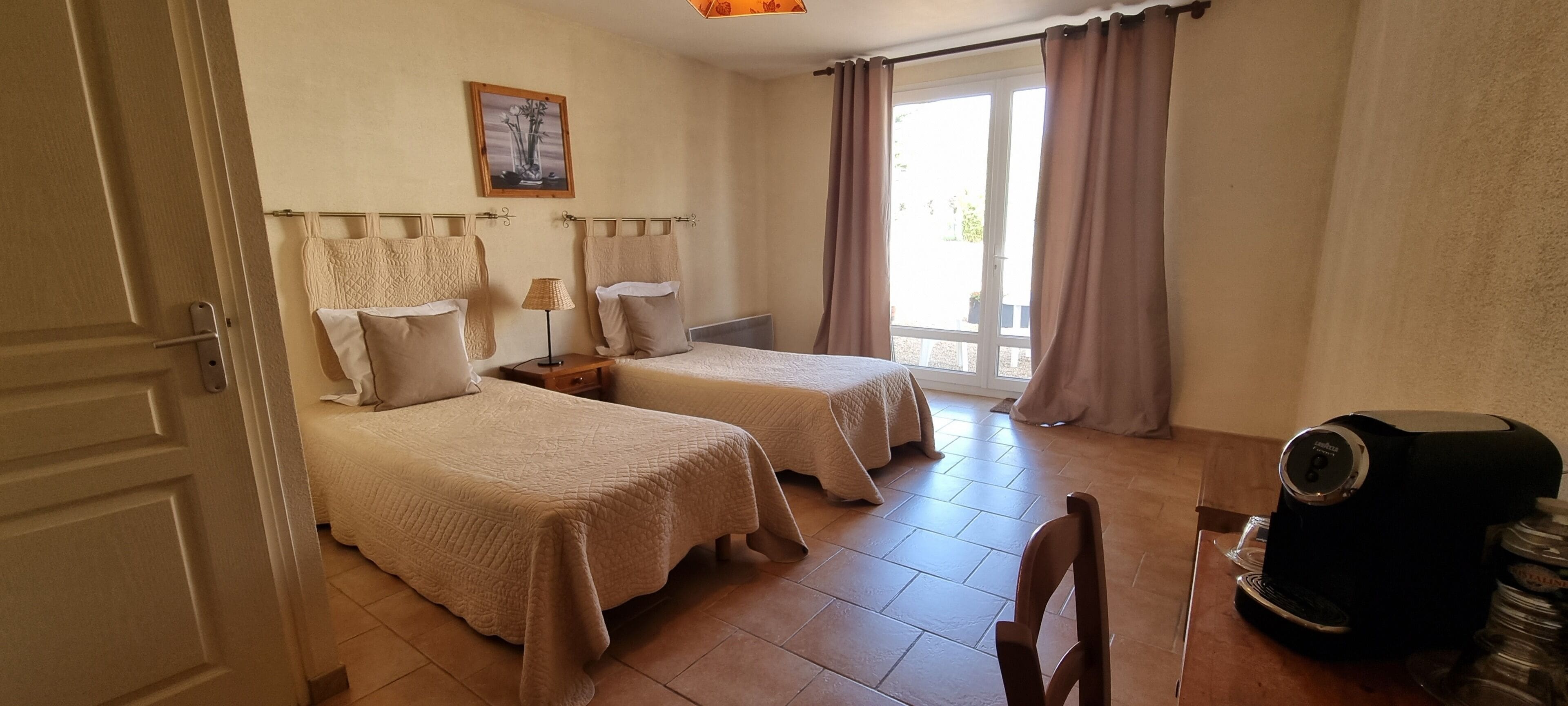 Habitación de hotel con dos camas, cafetera y vista al exterior.