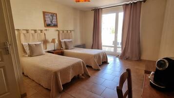 Habitación de hotel con dos camas, cafetera y vista al exterior.