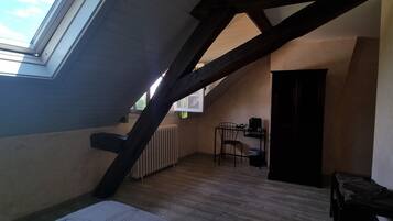 A sloped ceiling room with a skylight, a radiator, a chair, and a door.