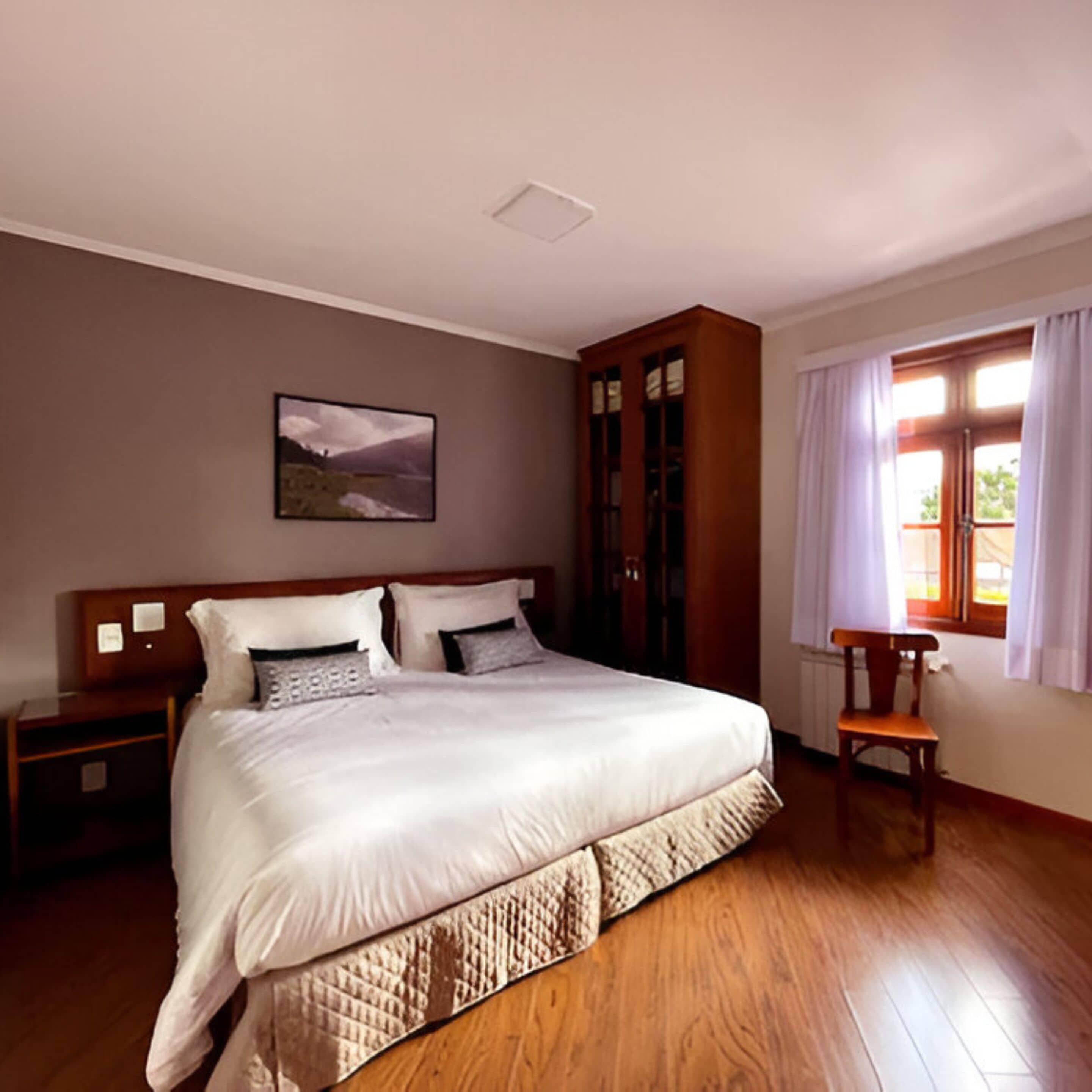 A bedroom with a large bed, wooden wardrobe, a nightstand, a chair, and a window with curtains.