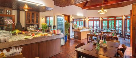 Un'ampia cucina con mobili in legno, un piano di lavoro in marmo e un'area pranzo con tavoli e sedie in legno.