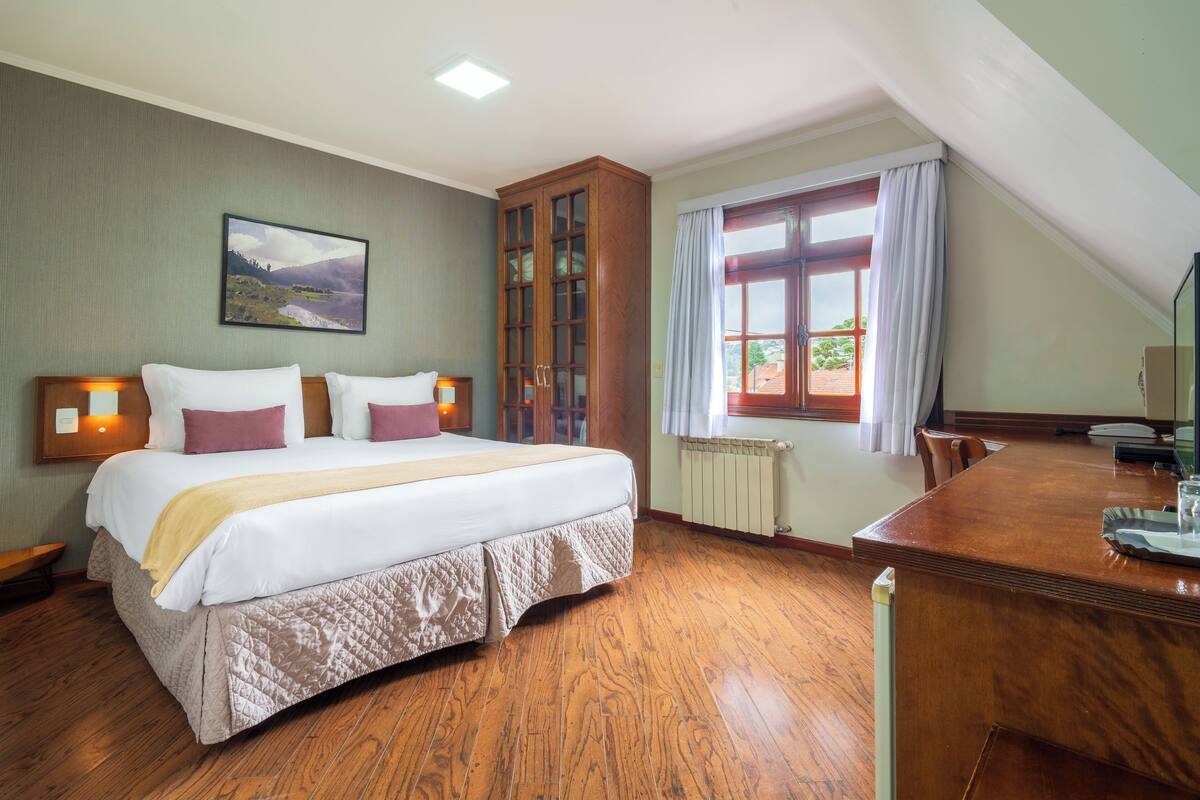 Een slaapkamer met een groot bed, een houten garderobe en een eettafel met stoelen.