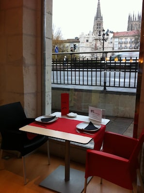 Un comedor con una mesa y sillas, y un ventanal que ofrece vistas a un paisaje urbano, incluyendo una catedral.