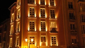 Un edificio de varios pisos con ventanas iluminadas y un estilo arquitectónico clásico.