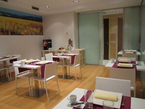 A dining area with white tables and chairs, a painting on the wall, and a door leading to another room. - Hotel Via Gotica (Burgos)