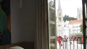 Una habitación de hotel con cama, ventana con vista a un edificio histórico y cortina.