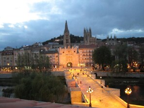 A historic cityscape with a prominent castle-like structure in the center, surrounded by a river and a bridge leading to it. - Hotel Via Gotica (Burgos)