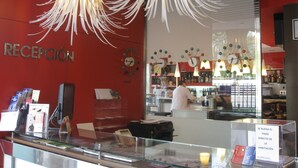 Zona de recepción con pared roja, un reloj y un mostrador con vitrina.