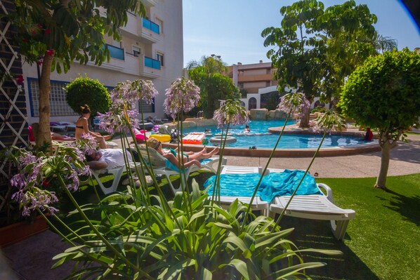 Alberca al aire libre, sombrillas en la alberca y camastros 