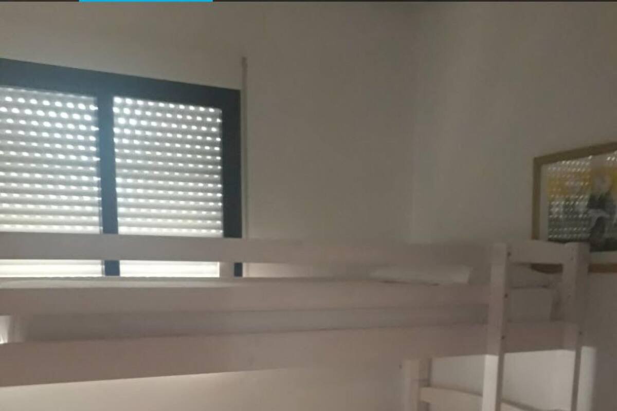 Habitación con literas, una ventana y un cuadro en la pared.