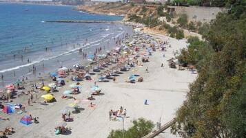 Una playa concurrida, con muchas sombrillas y gente disfrutando del mar.