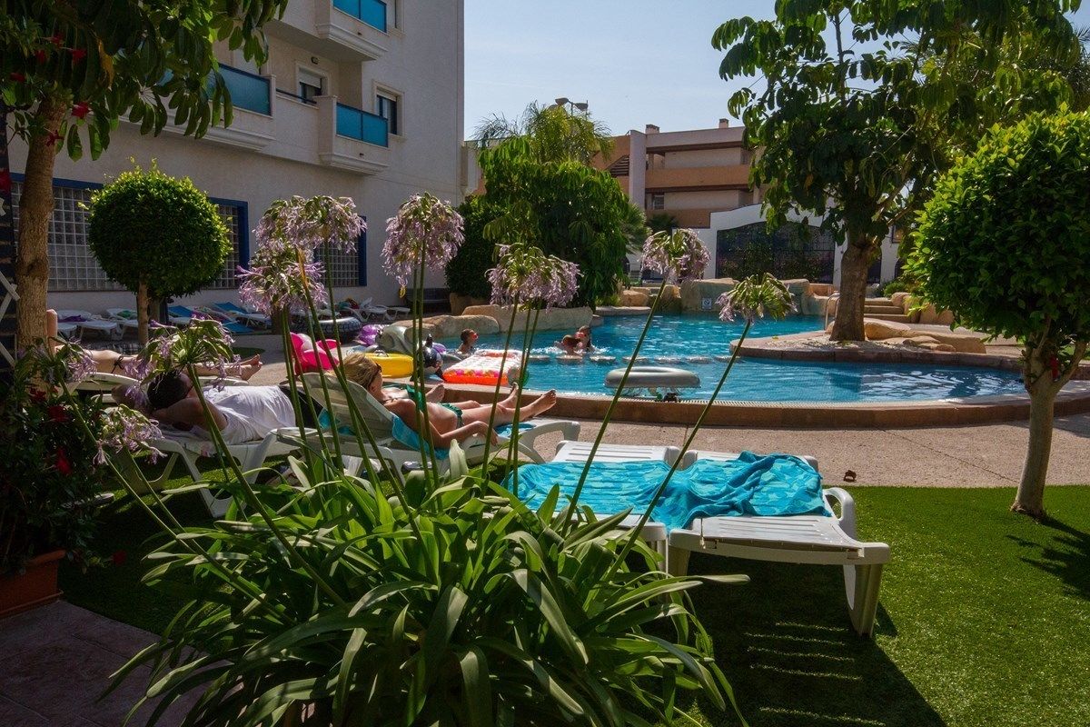 Un área de piscina con sillones reclinables y una pequeña cascada.