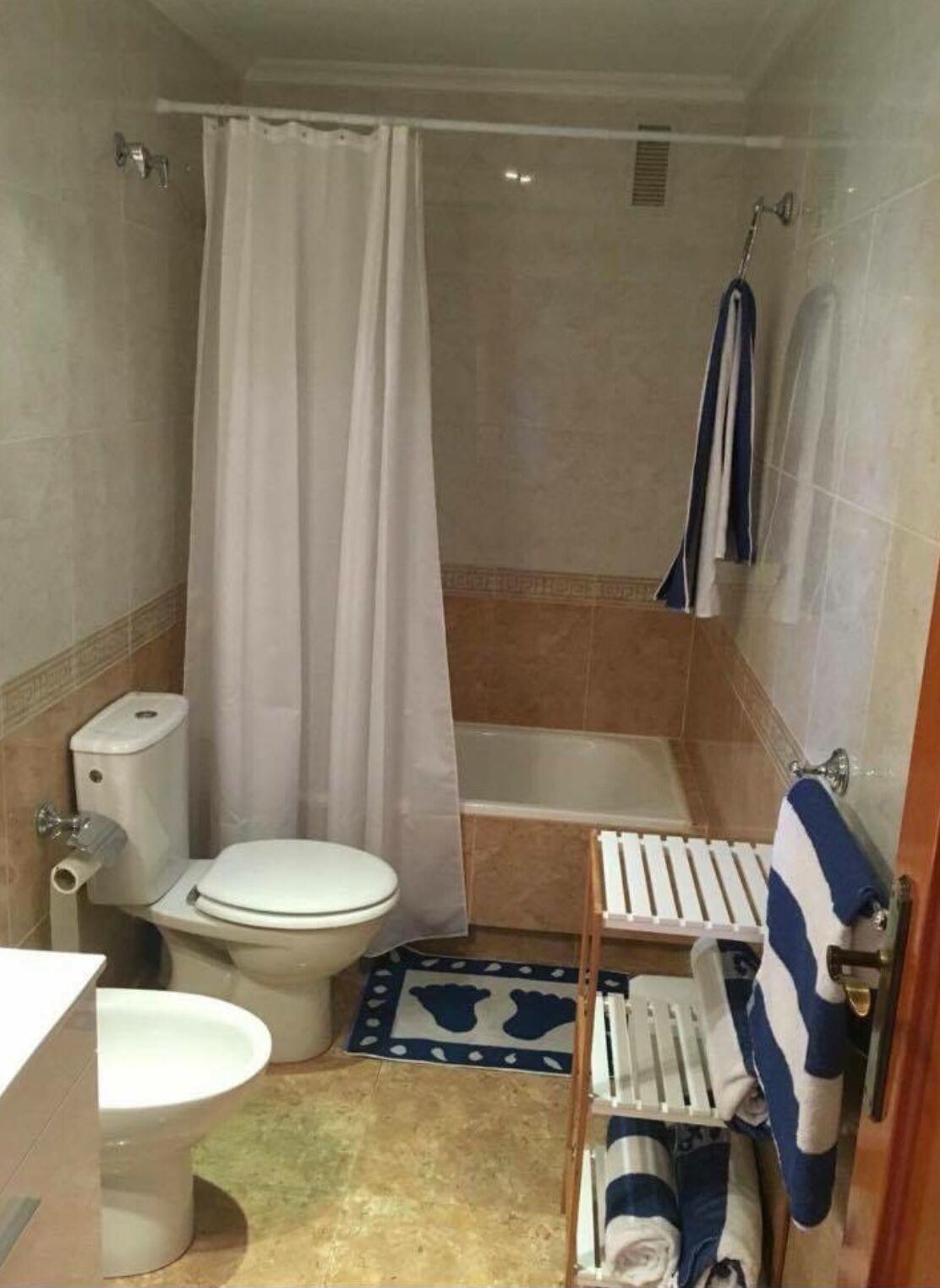 Un baño pequeño con inodoro, bañera, cortina de ducha y toallero.