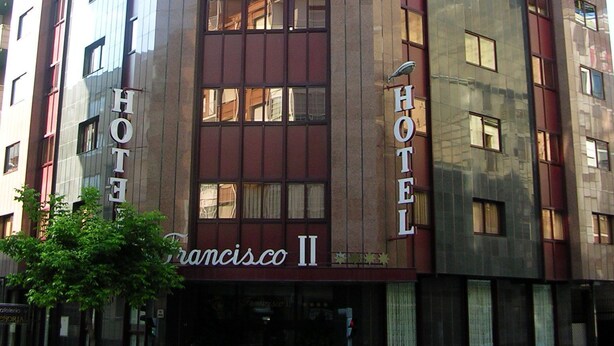 A multi-story hotel with a modern facade, featuring large windows and a prominent 'HOTEL' sign on the side. - Hotel Francisco II (Ourense)