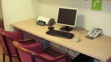 A desk with a computer, keyboard, mouse, and phone. There are two chairs and a printer.