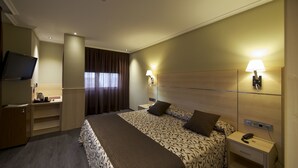 A hotel room with a large bed, bedside tables, a TV, and a window with curtains. - Hotel Francisco II (Ourense)