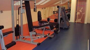 Un gimnasio con diversas máquinas de ejercicio y bancos.