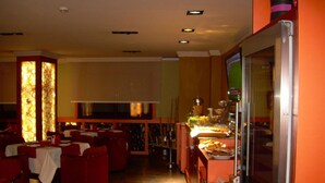 A restaurant with red chairs, a buffet, and a glass partition. - Hotel Francisco II (Ourense)