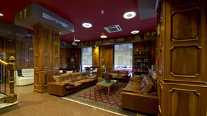 A spacious living area with leather sofas, a coffee table, and wooden paneling. - Hotel Francisco II (Ourense)