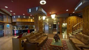 A spacious hotel lobby with leather sofas, a reception desk, and a kitchen area in the background. - Hotel Francisco II (Ourense)