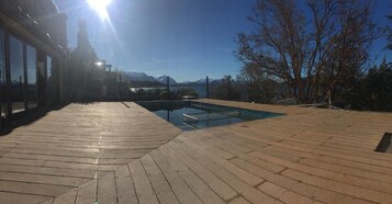 Una terraza de madera con piscina, con vistas a un paisaje montañoso.