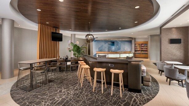 A modern lobby with a central bar area, seating arrangements, and a reception desk. - SpringHill Suites by Marriott Lafayette South at River Ranch (Lafayette)