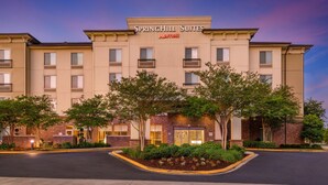A SpringHill Suites hotel with a brick facade, multiple balconies, and a landscaped entrance area. - SpringHill Suites by Marriott Lafayette South at River Ranch (Lafayette)