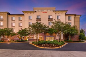 A SpringHill Suites hotel with a brick facade, multiple balconies, and a landscaped entrance area.