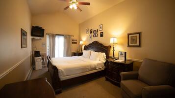 A hotel room with a bed, a desk, a chair, a television, and a ceiling fan.