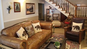 Ein Wohnzimmer mit einem braunen Ledersofa, einem Holzstuhl, einem Couchtisch und einer Treppe.