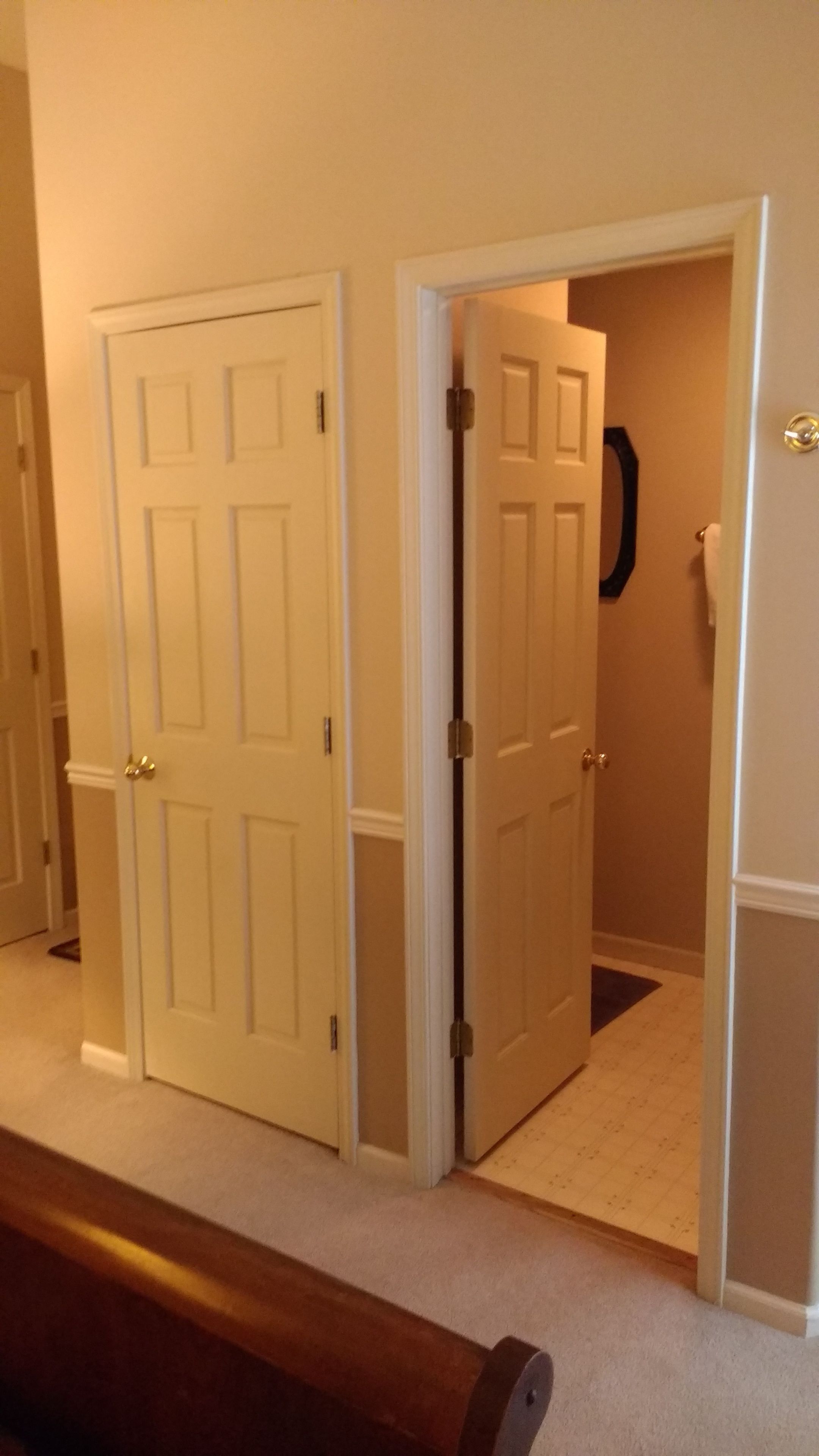 A hallway with two closed doors and a partially open door leading to another room.