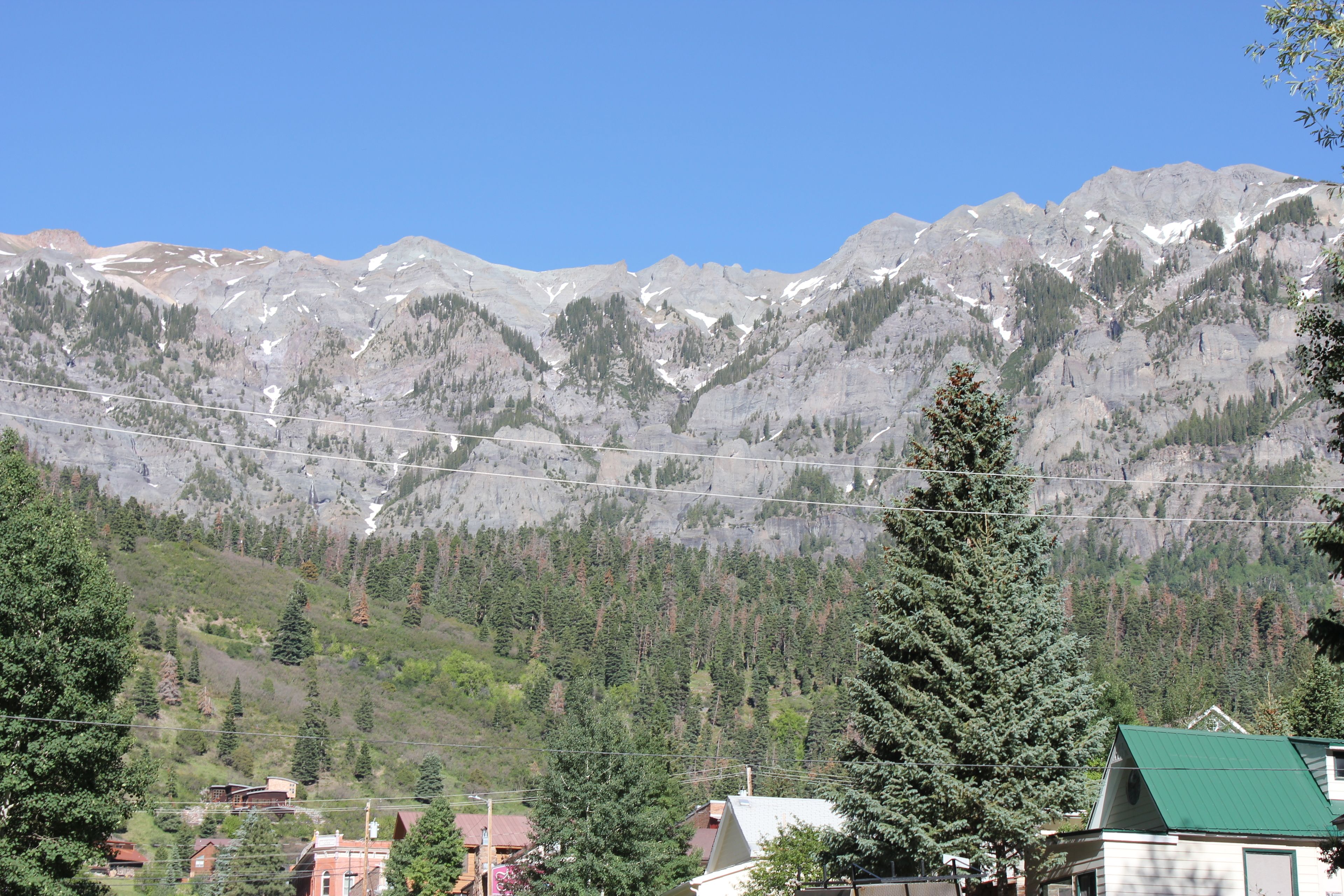 A mountain landscape with a house in the foreground and a clear blue sky.
