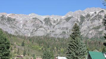 A mountain landscape with a house in the foreground and a clear blue sky.