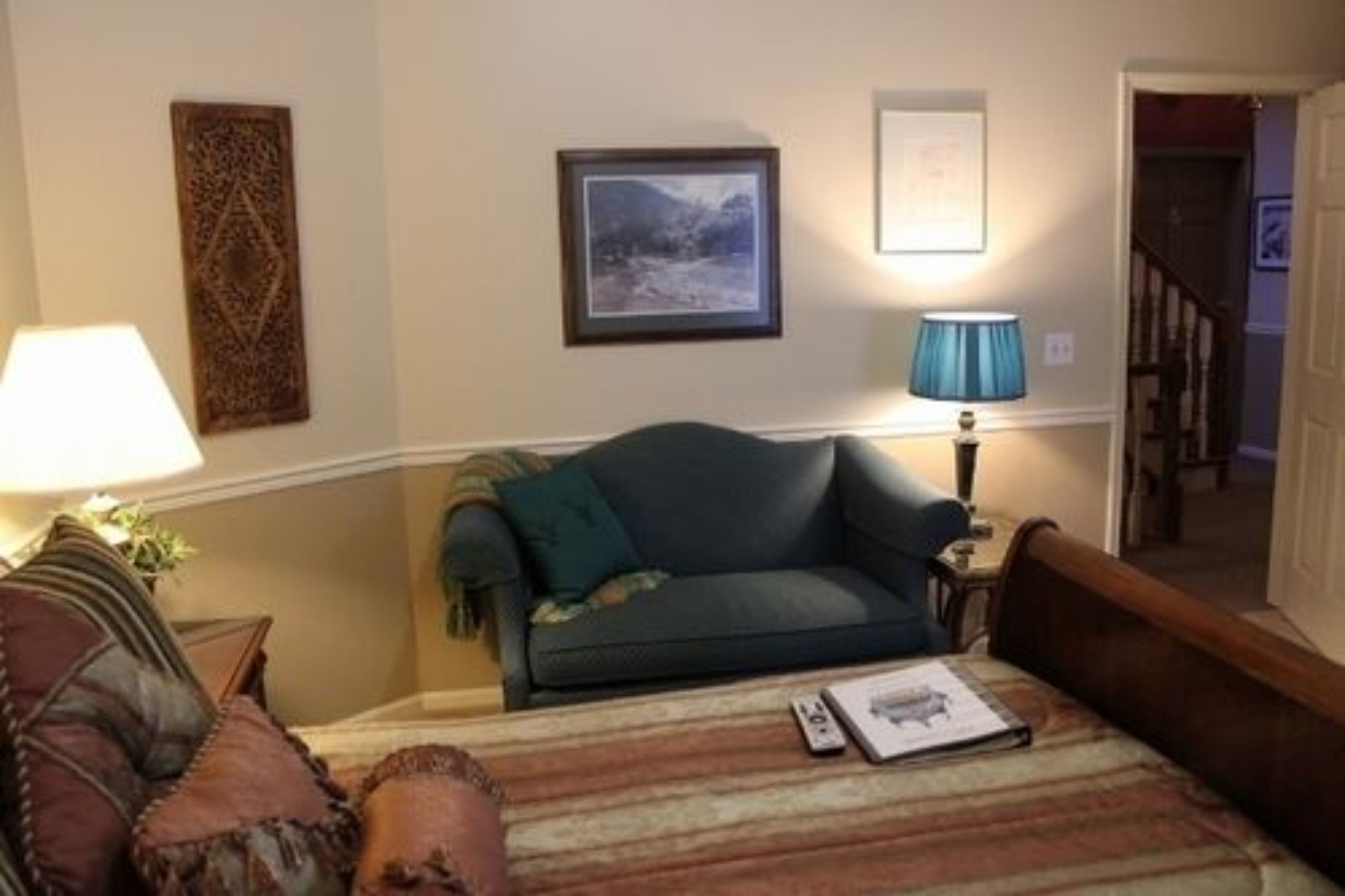 A cozy living room with a sofa, a lamp, and a framed picture on the wall.